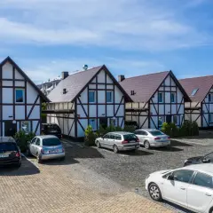 Tanie domki nad morzem w stylu szachulcowym, z parkingiem i samochodami.
