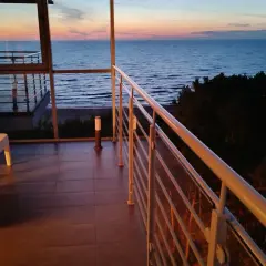 Dziwnówek noclegi z widokiem na morze. Balkon z białymi meblami i widokiem na spokojne morze o zachodzie słońca.