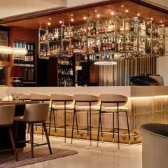Elegancki bar w hotelu Radisson Blu Kraków. Wnętrze z bogatą ekspozycją alkoholi, wygodnymi hokerami i stylowym oświetleniem.