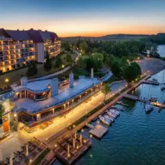 Zachód słońca nad jeziorem, gdzie cumują łodzie przy Hotelu Gołębiewski Mikołajki. Malowniczy widok na architekturę i wodę.