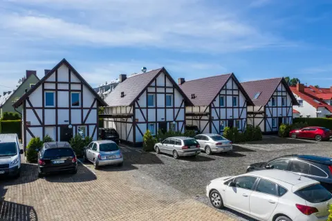 Tanie domki nad morzem w stylu szachulcowym, z parkingiem i samochodami.