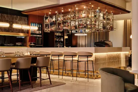 Elegancki bar w hotelu Radisson Blu Kraków. Wnętrze z bogatą ekspozycją alkoholi, wygodnymi hokerami i stylowym oświetleniem.
