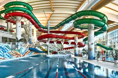 Wesołe zjeżdżalnie w hotelu z aquaparkiem zapraszają do zabawy w basenie. Kolorowe rury wiją się nad wodą, obiecując emocjonujące zjazdy.