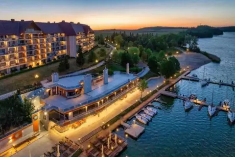 Zachód słońca nad jeziorem, gdzie cumują łodzie przy Hotelu Gołębiewski Mikołajki. Malowniczy widok na architekturę i wodę.