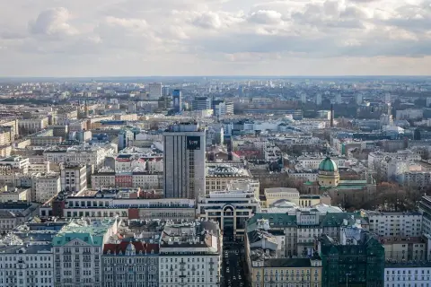 Rozległa panorama miasta, widok na warszawską dzielnicę z licznymi budynkami, w tym wieżowcem z napisem "Love".
