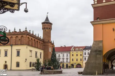 Rynek w Tarnowie zimową porą. Widać ratusz, kolorowe kamienice i świąteczną choinkę.