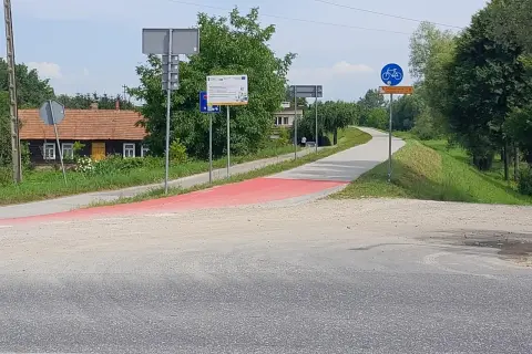 Czerwony pas wyznacza nowe trasy rowerowe w Tarnowie. W tle domki i zielone drzewa.
