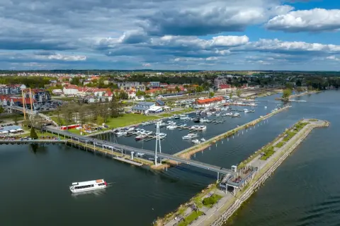 Widok na port jachtowy, miasto i jezioro. To stolica polskiego żeglarstwa, gdzie cumują liczne łodzie i statki.
