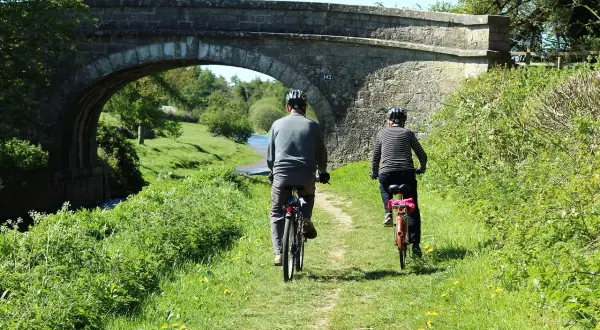 Dwie osoby na rowerach pod kamiennym mostem. Piękna pogoda sprzyja odkrywaniu tras rowerowych lubuskich.
