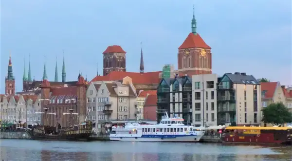 Statek wycieczkowy "Gryf" płynie przez Gdańsk, mijając zabytkowe kamienice i kościoły.