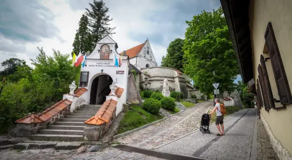 Sanktuarium na lubelszczyźnie, z kamiennymi schodami i brukowaną uliczką, gdzie ojciec pcha wózek.