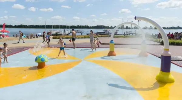 Dzieci bawią się na wodnym placu zabaw przy plaży nad jeziorem Zegrzyńskim.