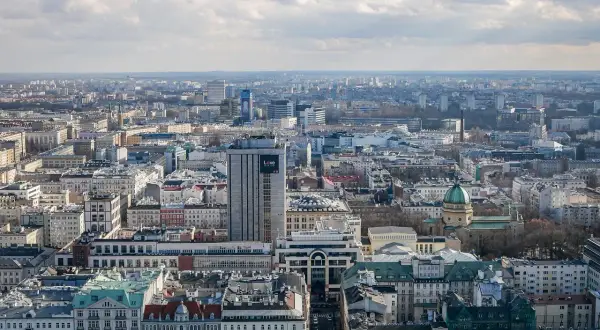 Rozległa panorama miasta, widok na warszawską dzielnicę z licznymi budynkami, w tym wieżowcem z napisem "Love".