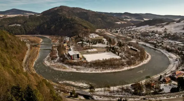 Piwniczna-Zdrój w Beskidzie Sądeckim, z meandrującą rzeką Poprad, ośnieżonymi wzgórzami i zabudowaniami.