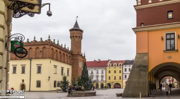 Rynek w Tarnowie zimową porą. Widać ratusz, kolorowe kamienice i świąteczną choinkę.