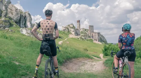 Dwaj rowerzyści podziwiają ruiny zamku na Szlaku Orlich Gniazd. Ile dni potrzeba na przejechanie go rowerem?