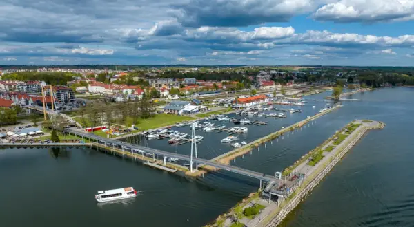 Widok na port jachtowy, miasto i jezioro. To stolica polskiego żeglarstwa, gdzie cumują liczne łodzie i statki.