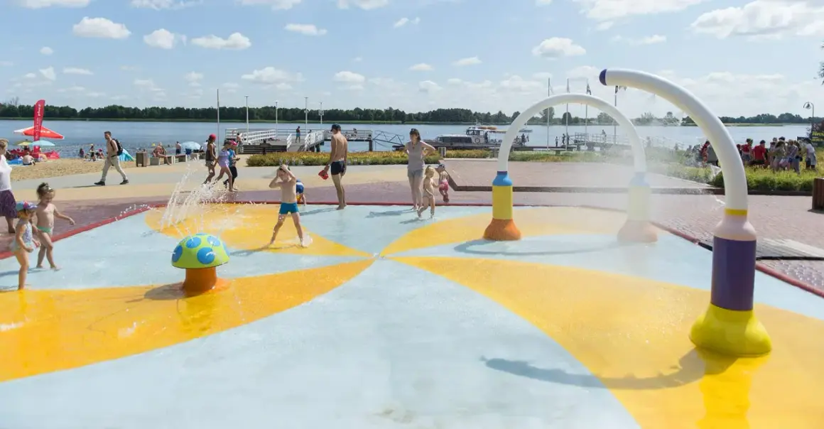 Dzieci bawią się na wodnym placu zabaw przy plaży nad jeziorem Zegrzyńskim.