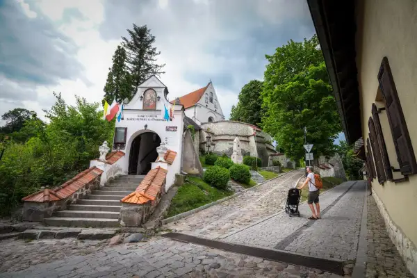 Sanktuarium na lubelszczyźnie, z kamiennymi schodami i brukowaną uliczką, gdzie ojciec pcha wózek.