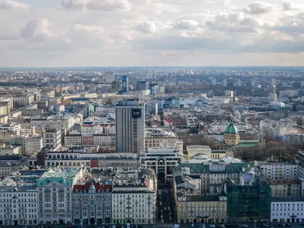 Rozległa panorama miasta, widok na warszawską dzielnicę z licznymi budynkami, w tym wieżowcem z napisem "Love".