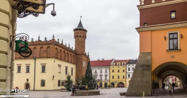 Rynek w Tarnowie zimową porą. Widać ratusz, kolorowe kamienice i świąteczną choinkę.