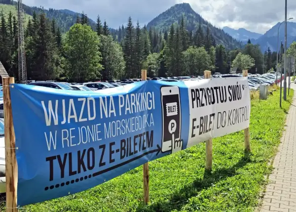 Wjazd na parking w Morskim Oku tylko z e-biletem. Przygotuj swój e-bilet do kontroli. Tło to góry i las.