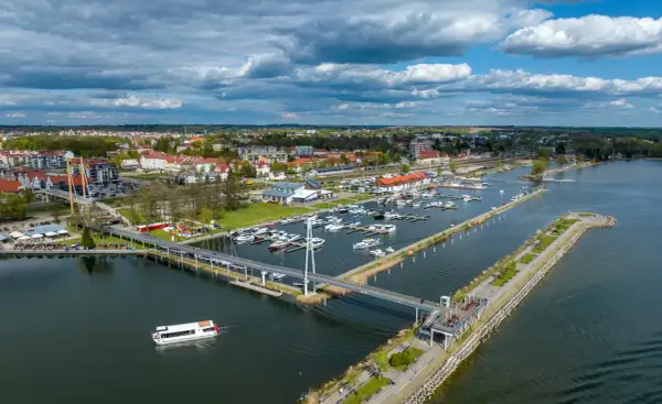 Widok na port jachtowy, miasto i jezioro. To stolica polskiego żeglarstwa, gdzie cumują liczne łodzie i statki.